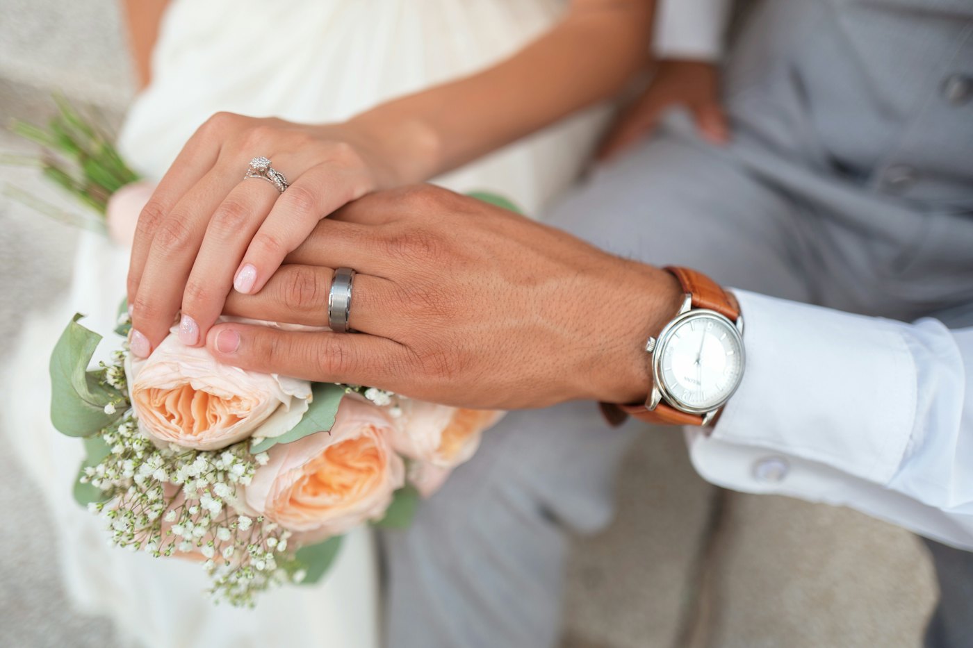 A bride and groom holding hands, showing their rings